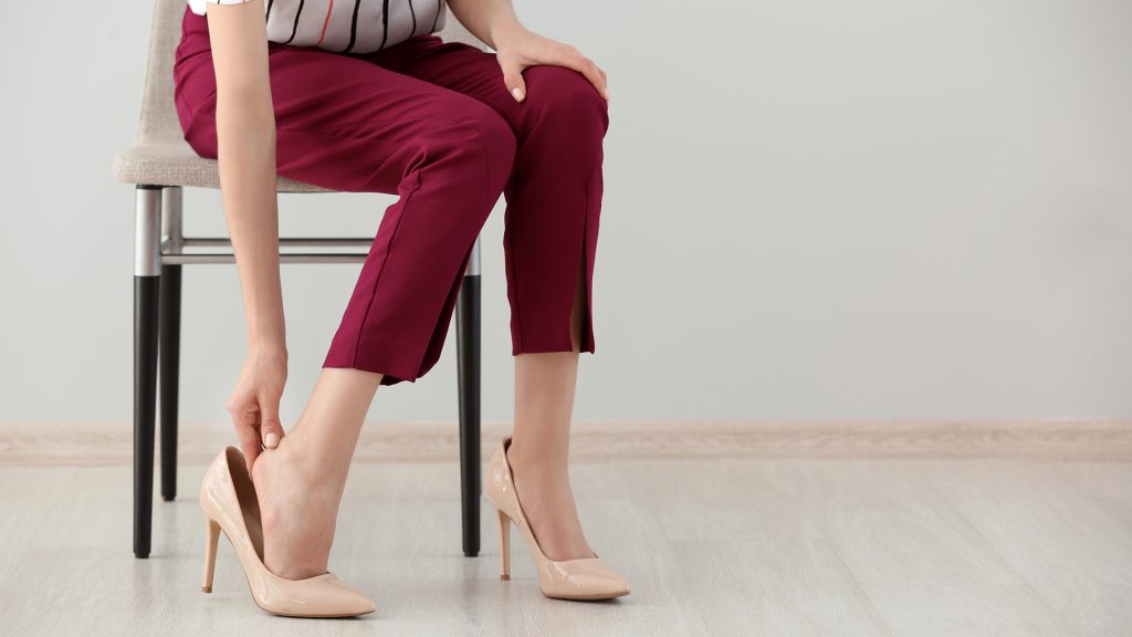 Tired young woman feeling ache in legs indoors
